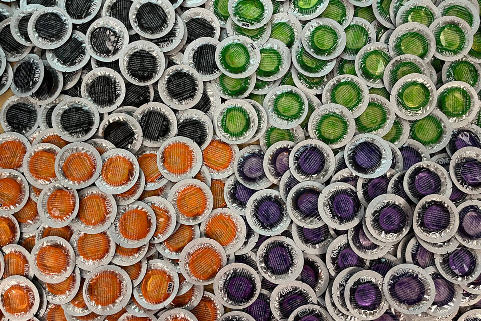 Black, green, orange, and purple condoms in individual packaging.